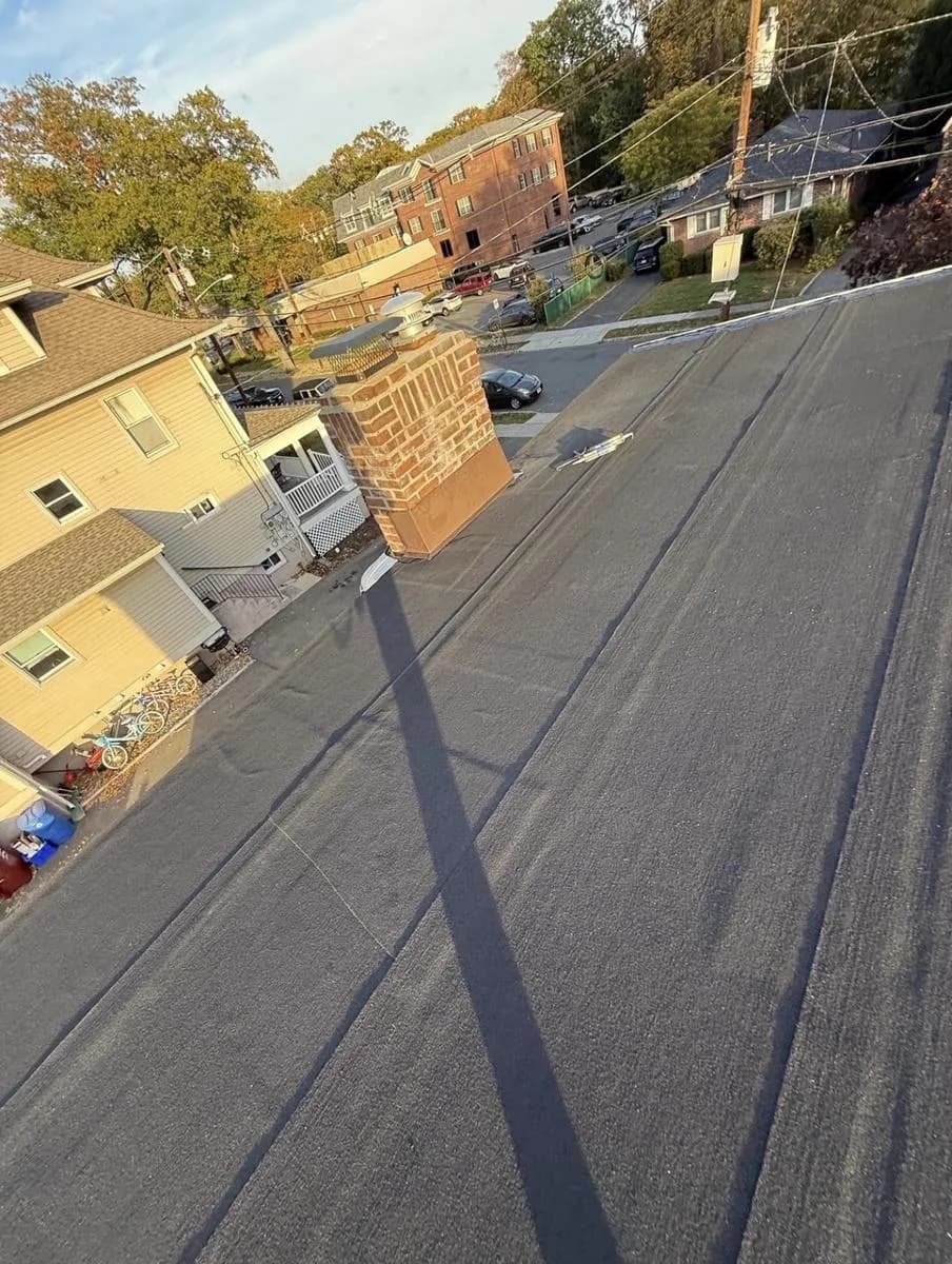 New Modified Bitumen flat roof installed with brick chimney in foreground — Nutley