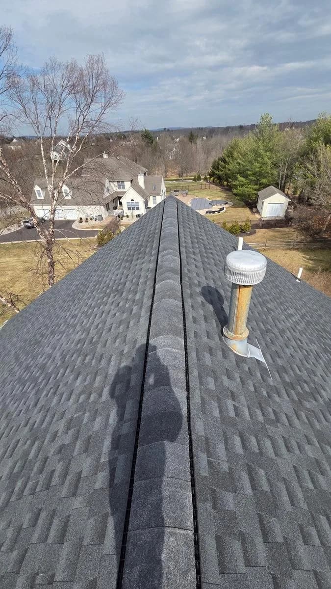Wide ridge view of new GAF Timberline HDZ Charcoal roof showing ventilation and pipe collars — Raritan Township
